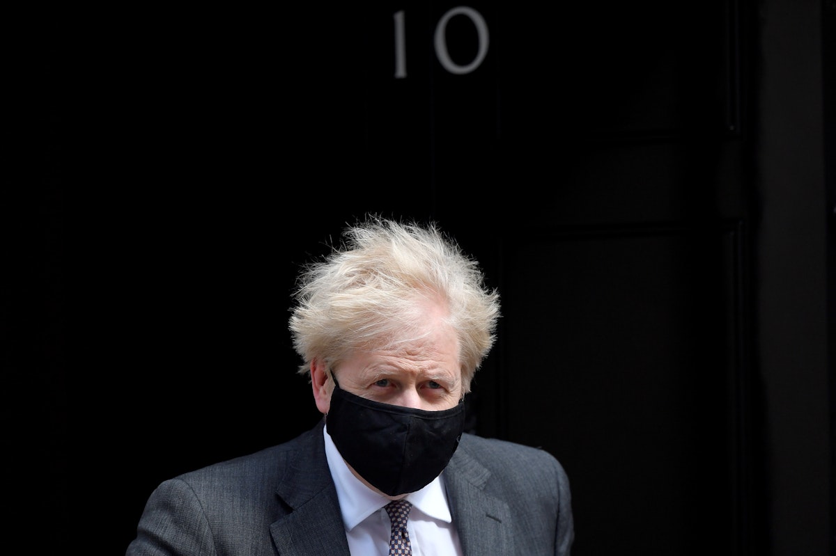 رئيس الوزراء البريطاني بوريس جونسون يرتدي كمامة، بينما يغادر مكتبه في داونينغ ستريت في العاصمة لندن - REUTERS