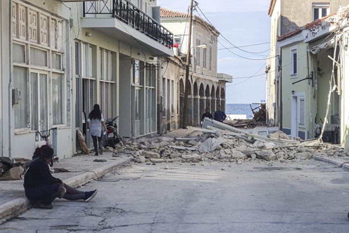 أشخاص بجوار منزل مدمر بعد زلزال ضرب جزيرة ساموس اليونانية، 30 أكتوبر 2020 - AFP