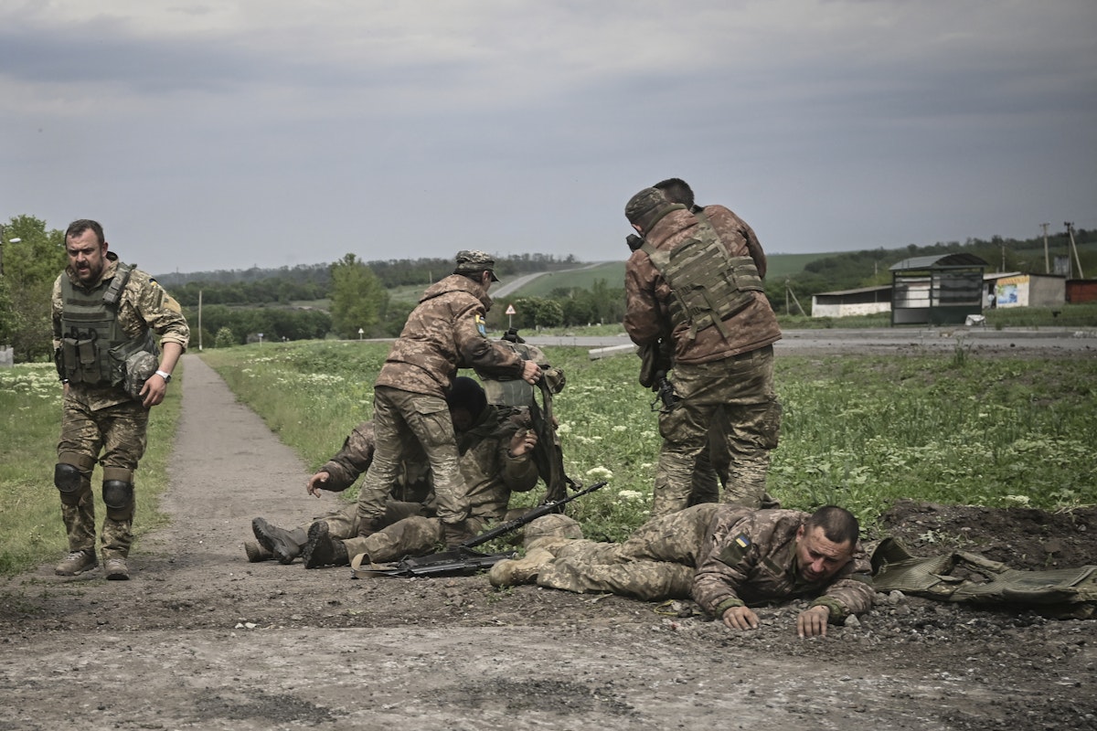جنود أوكرانيون يساعدون رفاقهم في مكان ليس ببعيد عن خط المواجهة في منطقة دونباس بشرق أوكرانيا. 21 مايو 2022 - AFP
