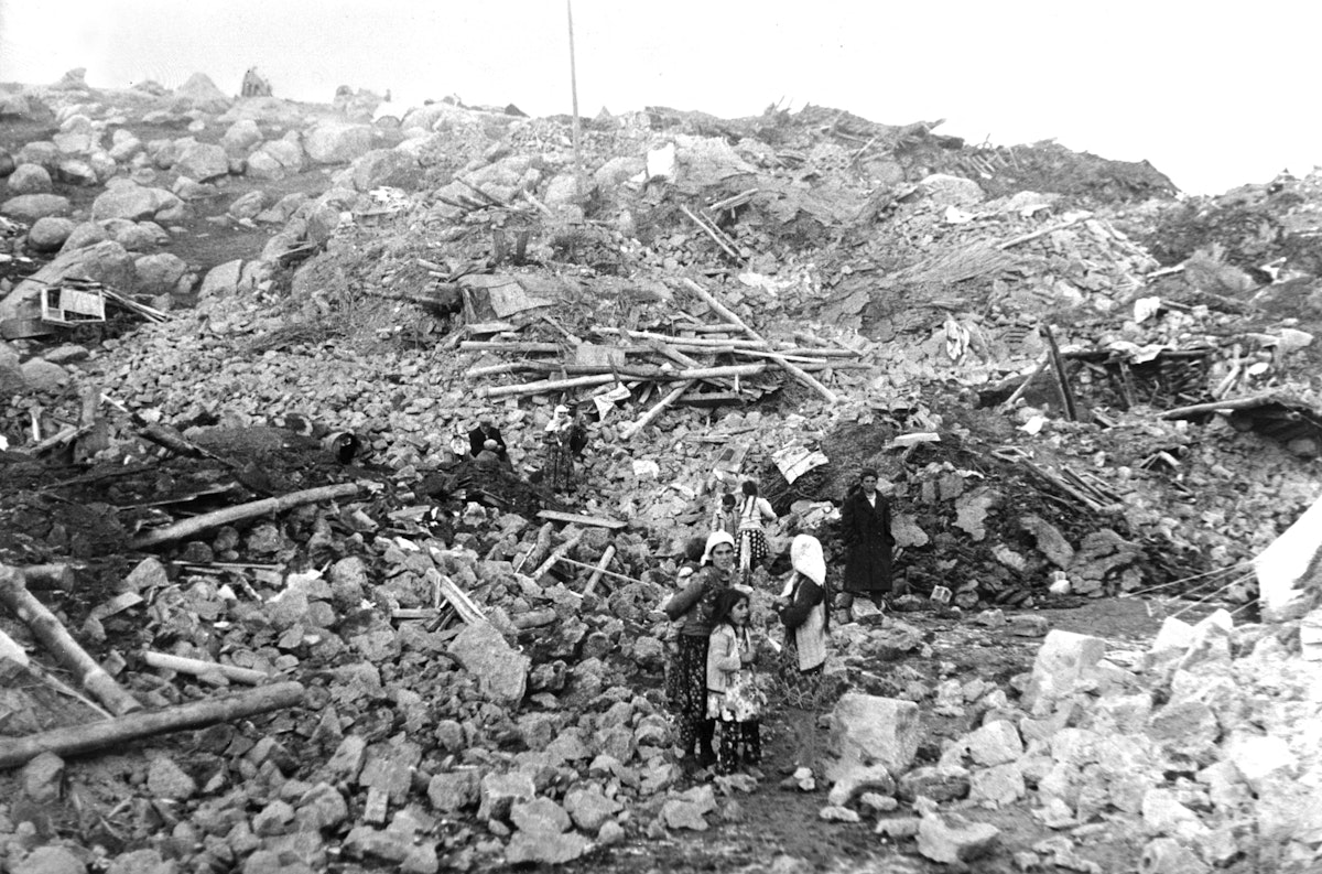 أسرة تقف أمام منازل منهارة بعد زلزال ضرب جالديران في تركيا، 27 نوفمبر 1976 - AFP